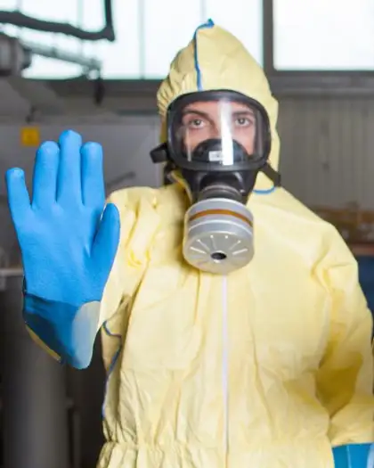 Frontline worker wearing a canister mask and chemical protective coverall and chemical protective gloves