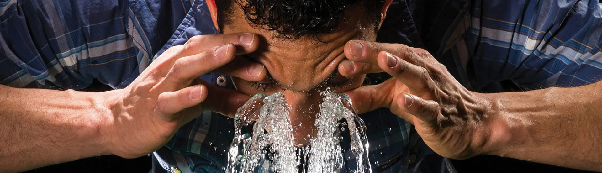 Man washing eyes in emergency eye wash station