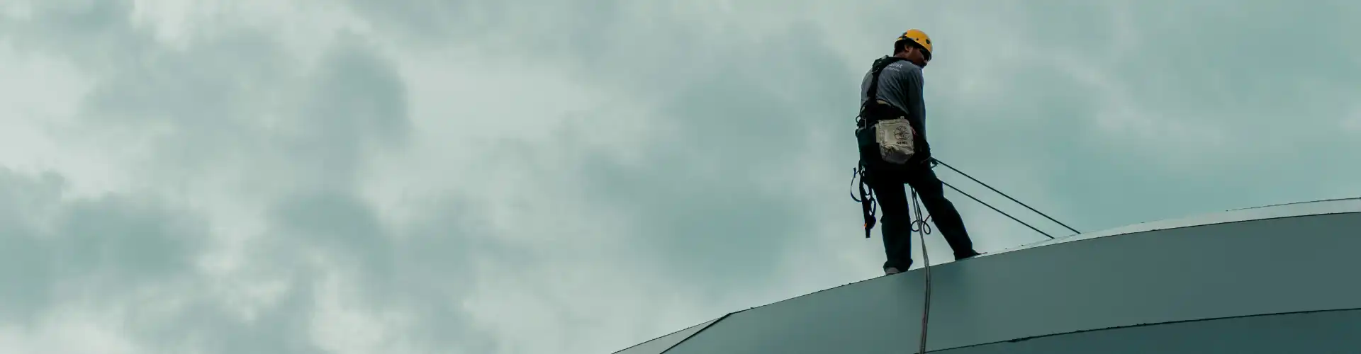 Man working at height with body harness and safety helmet and ropes